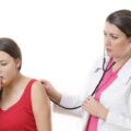 persona tosiendo mientras el medico la revisa