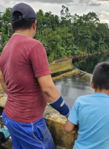 Una familia observa un derrame de petróleo en el río Viche