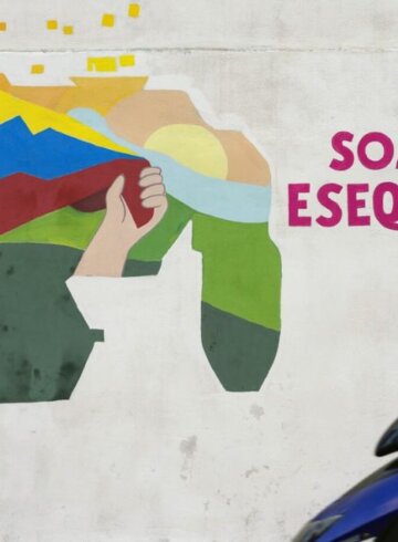 Un joven conduce una motocicleta frente a un mural con un mapa de Venezuela que incluye al territorio de Esequibo