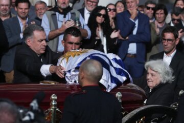 El presidente de Uruguay, Yamandú Orsi, extiende una bandera sobre el ataúd del exmandatario uruguayo José "Pepe" Mujica.