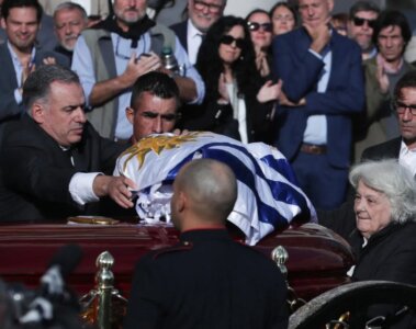 El presidente de Uruguay, Yamandú Orsi, extiende una bandera sobre el ataúd del exmandatario uruguayo José "Pepe" Mujica.