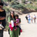 Personas caminando con niños en la frontera