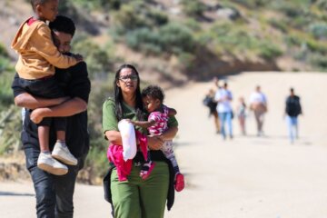Personas caminando con niños en la frontera
