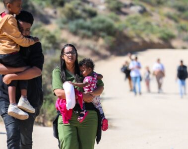 Personas caminando con niños en la frontera