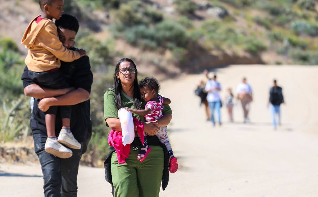 Personas caminando con niños en la frontera